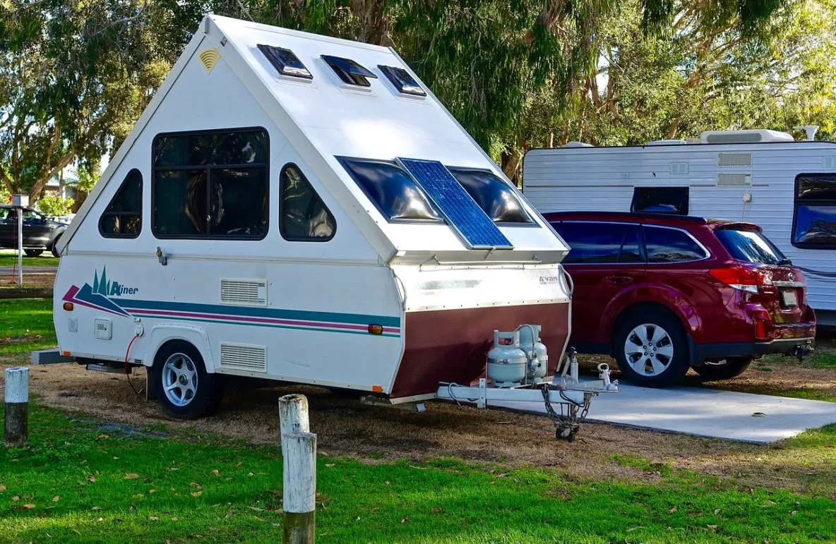 Aliner A-frame popup camper with solar panels at campground