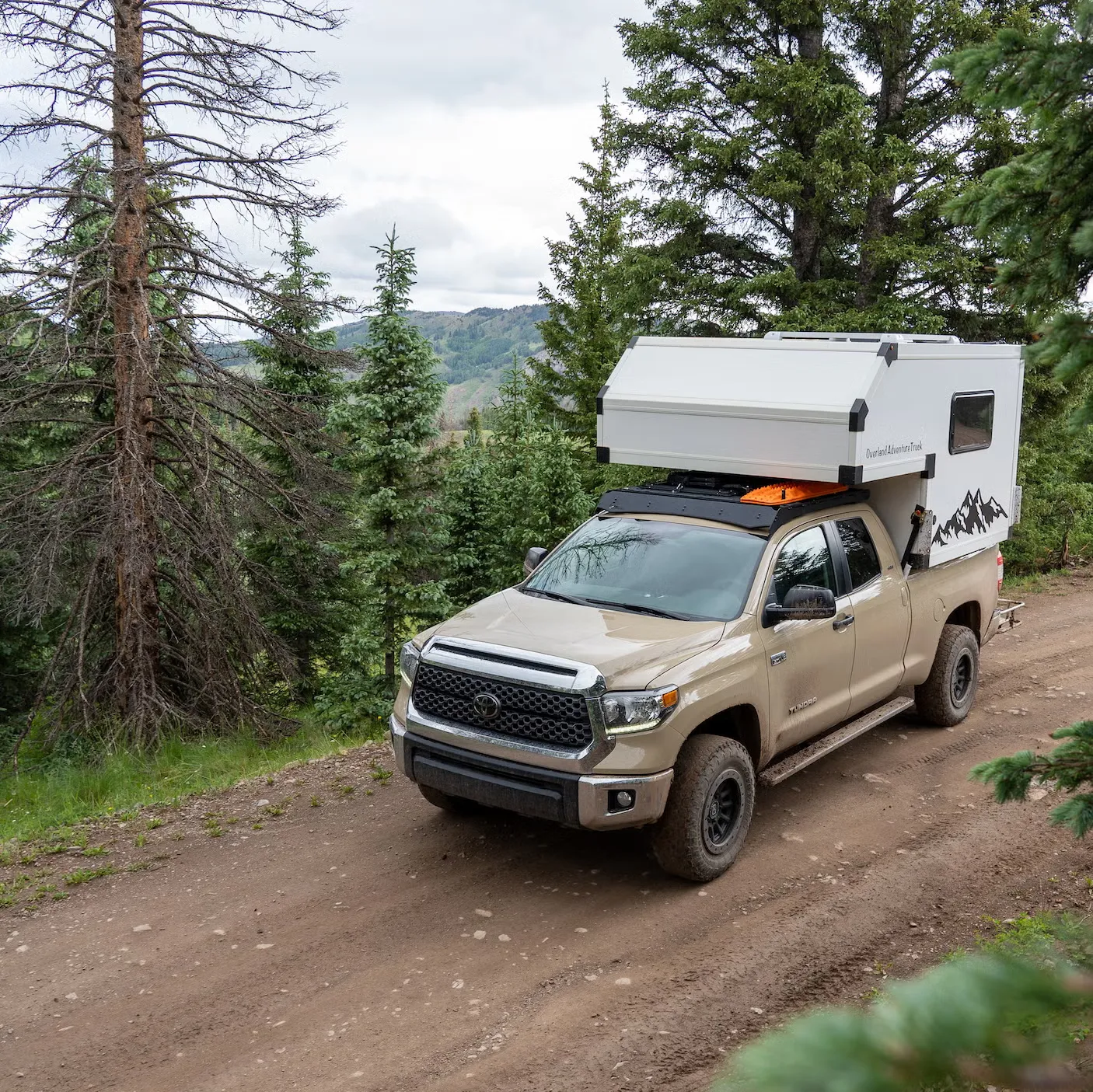 Toyota Tundra with popup truck camper on a mountain trail
